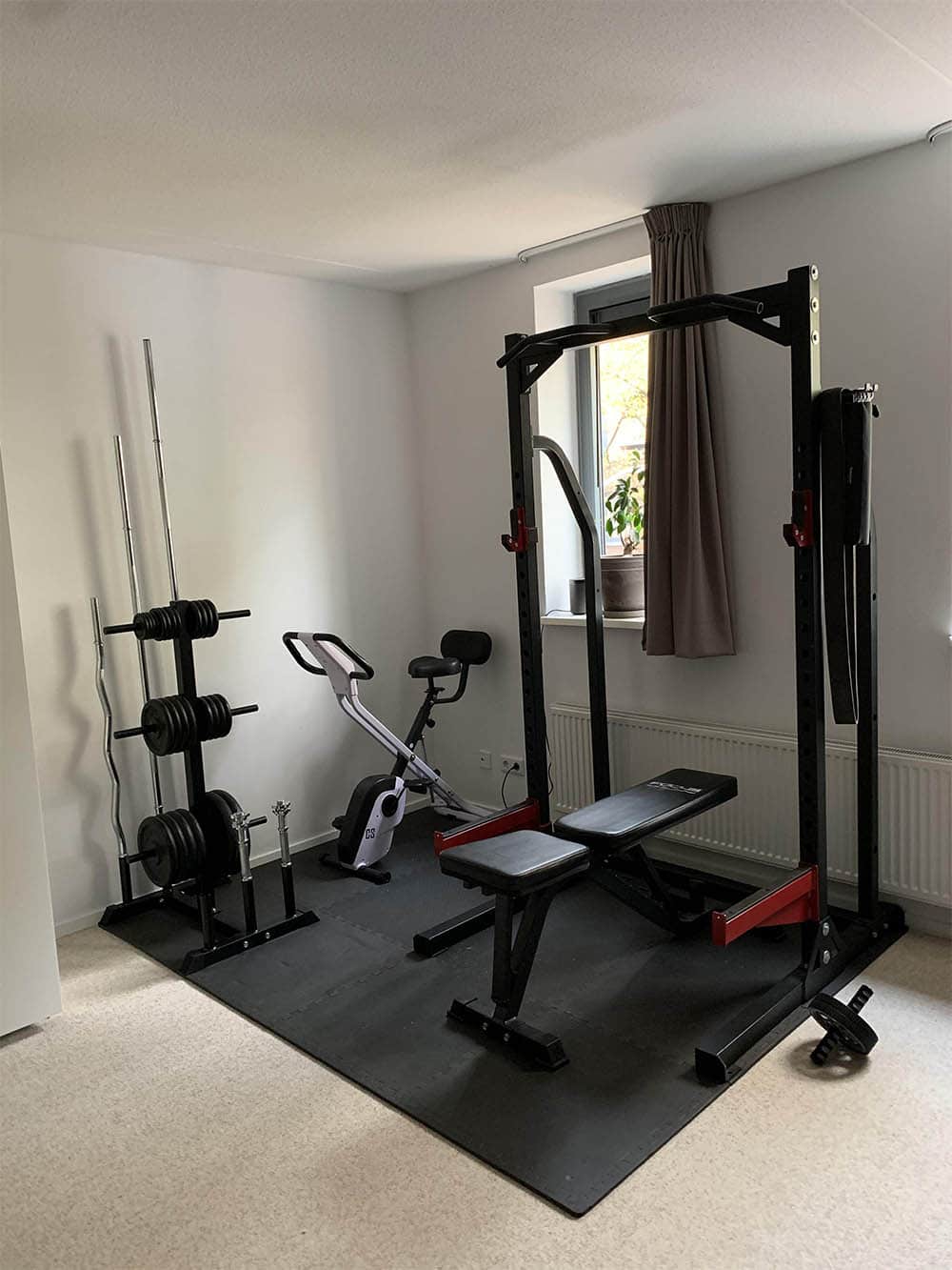 small home gym in the corner of the room with a squat rack and exercise bike