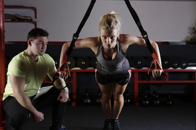 woman training at gym with guidance of PT