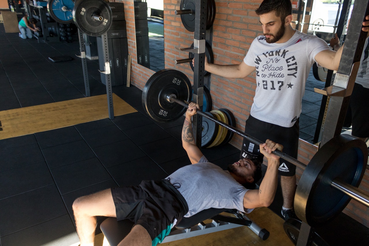man doing bench press with a spotter