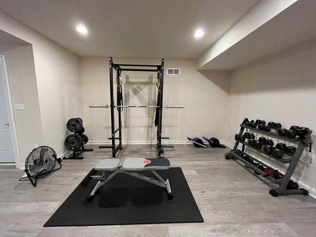 home gym with power rack, weight bench, and dumbbell storage racks