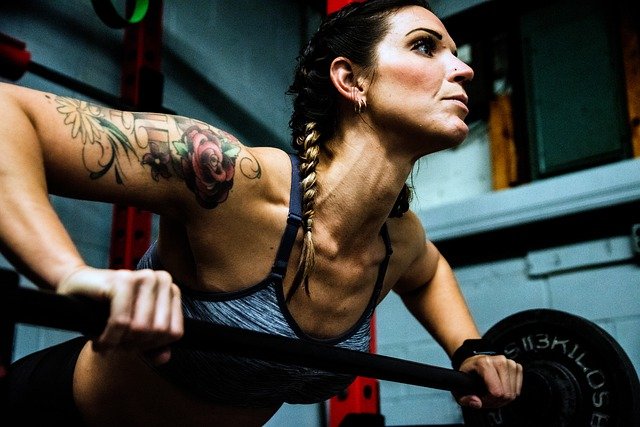 woman training muscles with barbell