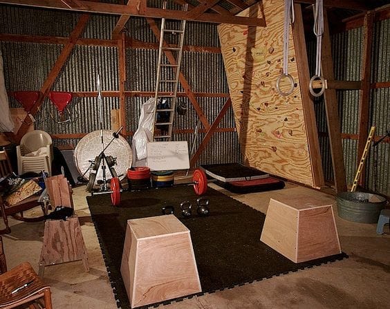 small shed gym with climbing wall and plyo boxes