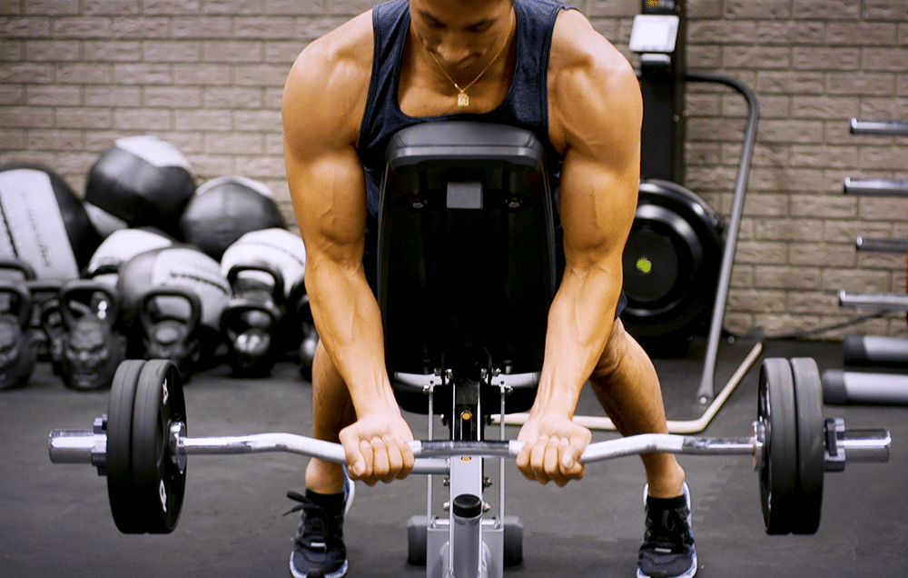 man doing incline bench spider curls with a curl bar