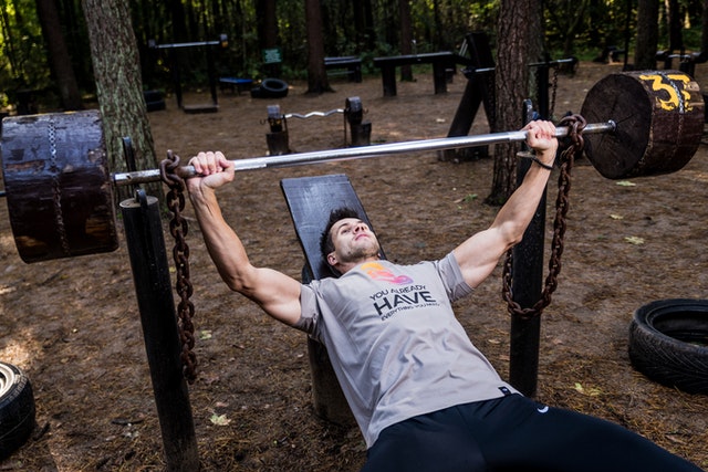 man in gray shirt working out on homemade wooden bench press