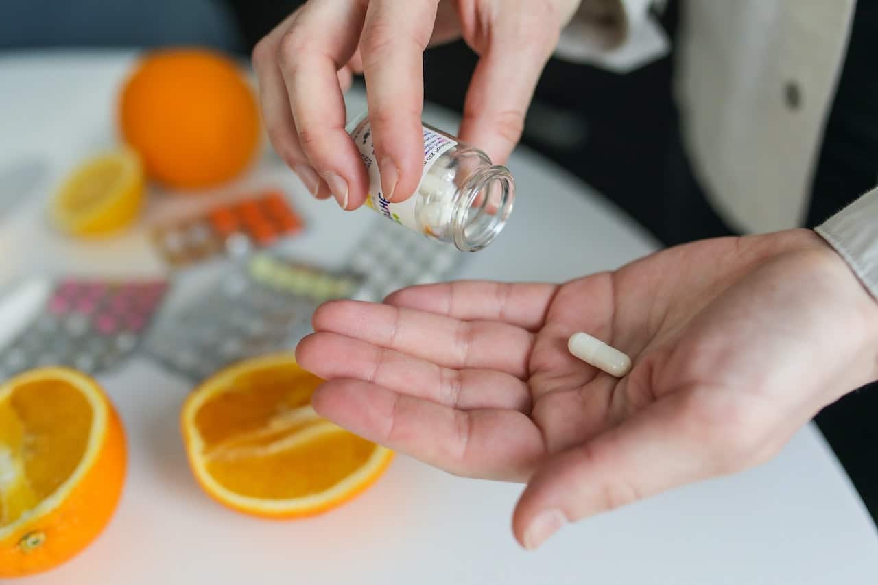 person pouring supplement pills in their hand