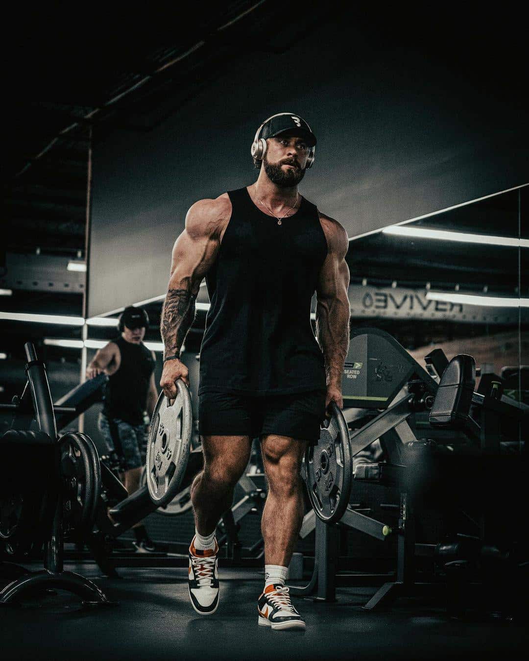Chris Bumstead Carrying Two Weight Plates Around the Gym