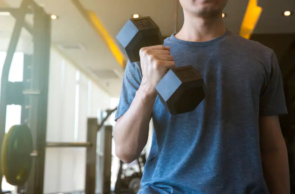 Gym Newbie in Blue Shirt Doing Dumbbell Bicep Curls