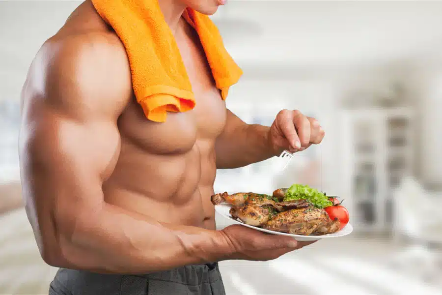 shirtless man with an orange towel around his neck and a plate of food